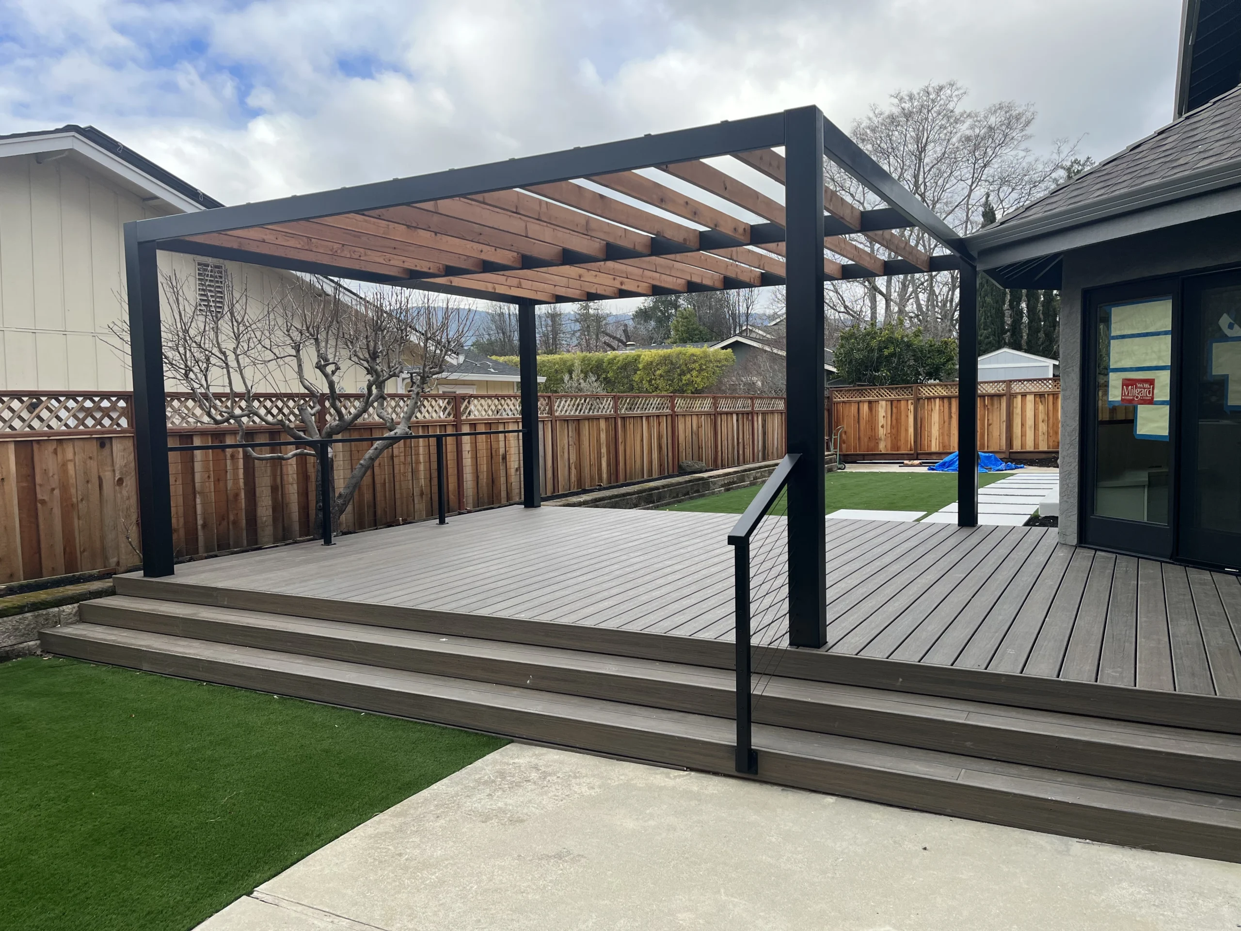 Composite deck with black steel pergola and cable railing built by JBC
