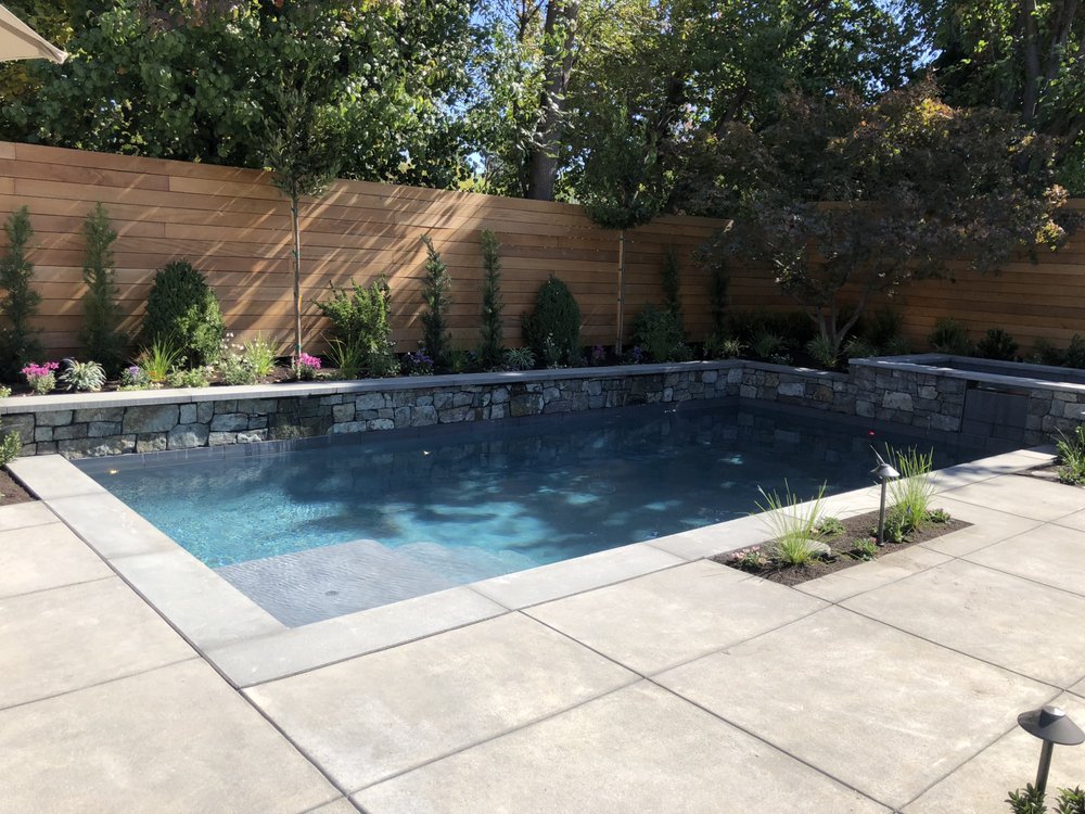 Backyard pool with stone retaining wall and cedar fence